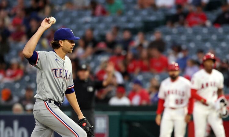Rangers pitcher Jacob deGrom holds up a new ball on the mound as an Angels runner stands at first