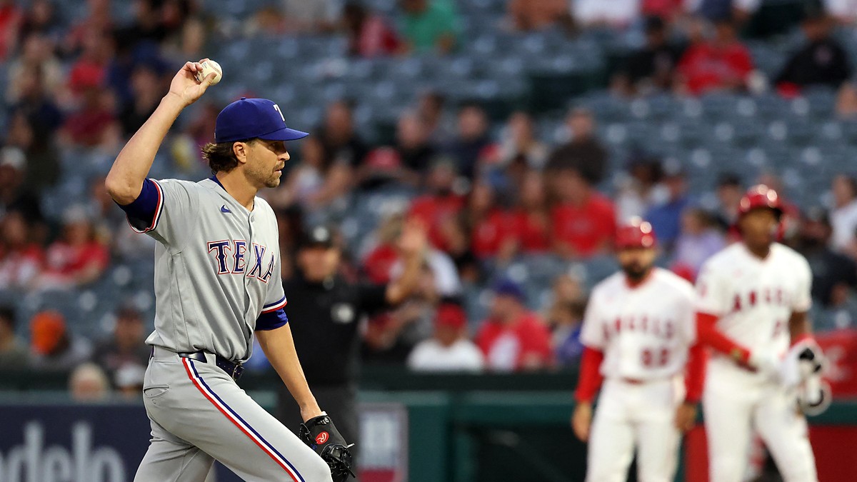 Rangers pitcher Jacob deGrom holds up a new ball on the mound as an Angels runner stands at first