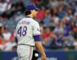 Rangers pitcher Jacob deGrom stands on the mound holding the ball after giving up a hit