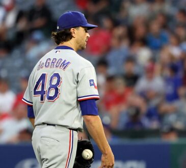 Rangers pitcher Jacob deGrom stands on the mound holding the ball after giving up a hit