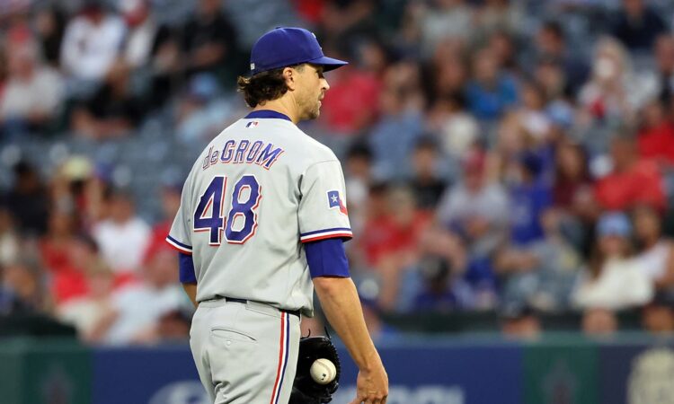 Rangers pitcher Jacob deGrom stands on the mound holding the ball after giving up a hit