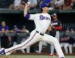 Alt Text: Texas Rangers pitcher Jacob deGrom delivers a pitch at Globe Life Field, the ball cocked behind his head.