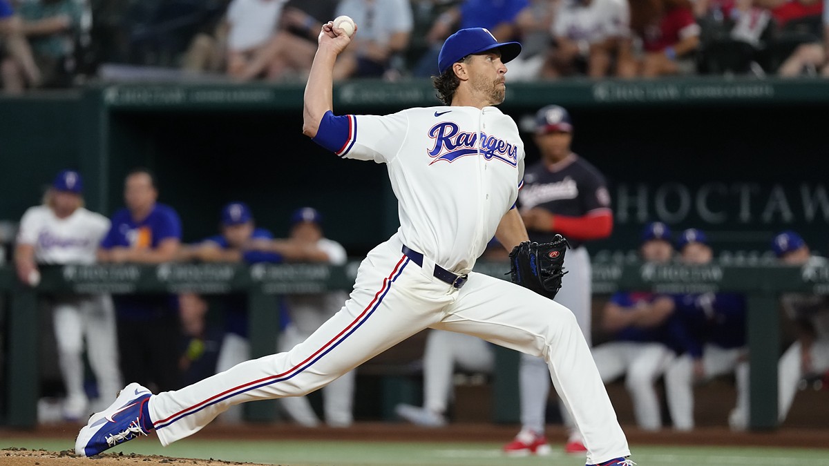 Alt Text: Texas Rangers pitcher Jacob deGrom delivers a pitch at Globe Life Field, the ball cocked behind his head.