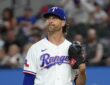 Texas Rangers pitcher Jacob deGrom stands on the mound with his glove up, looking toward the outfield after a strikeout.