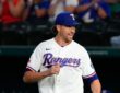 Texas Rangers pitcher Jacob deGrom jogs out to the mound in his white home uniform, smiling.