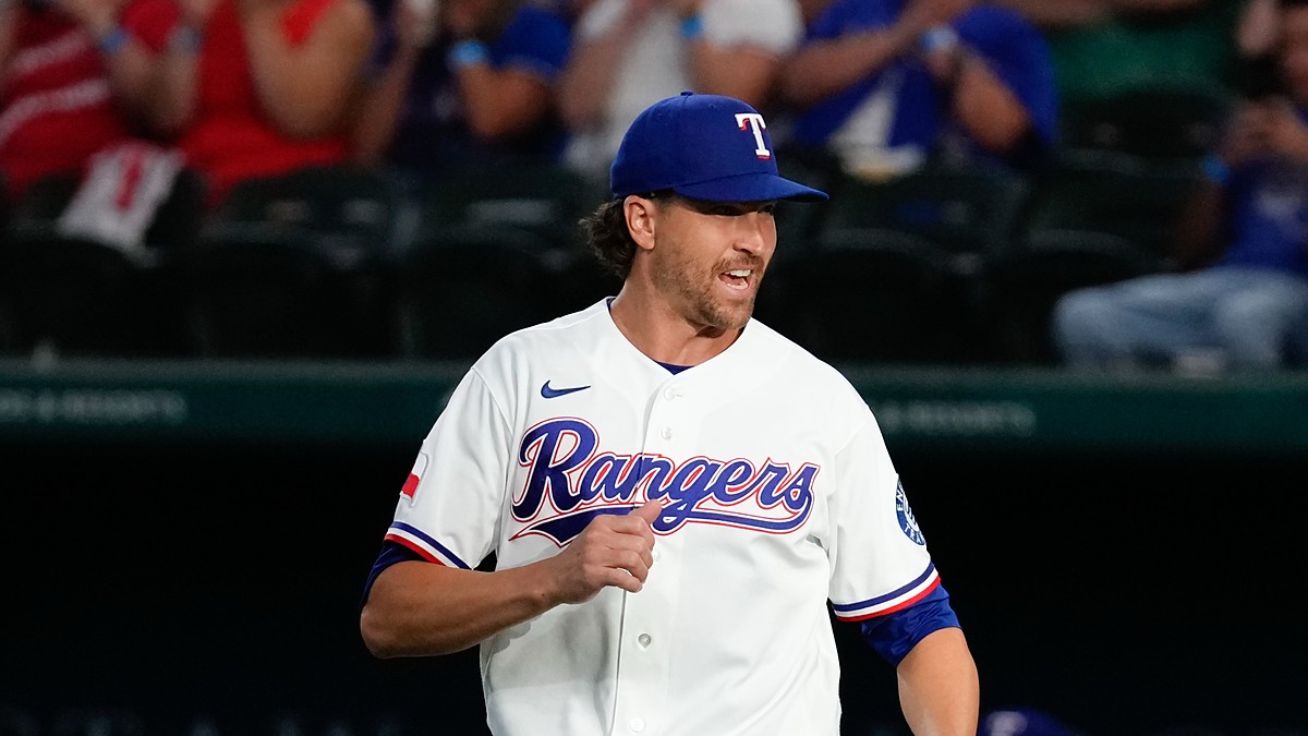 Texas Rangers pitcher Jacob deGrom jogs out to the mound in his white home uniform, smiling.