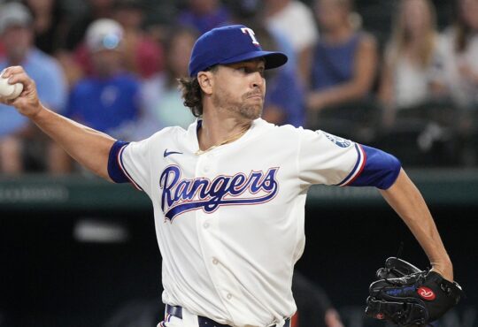 Rangers pitcher Jacob deGrom releases a pitch from the mound in a home white uniform