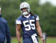 Dallas Cowboys linebacker Jaishawn Barham smiles toward a coach while standing on the practice field in helmet and jersey.