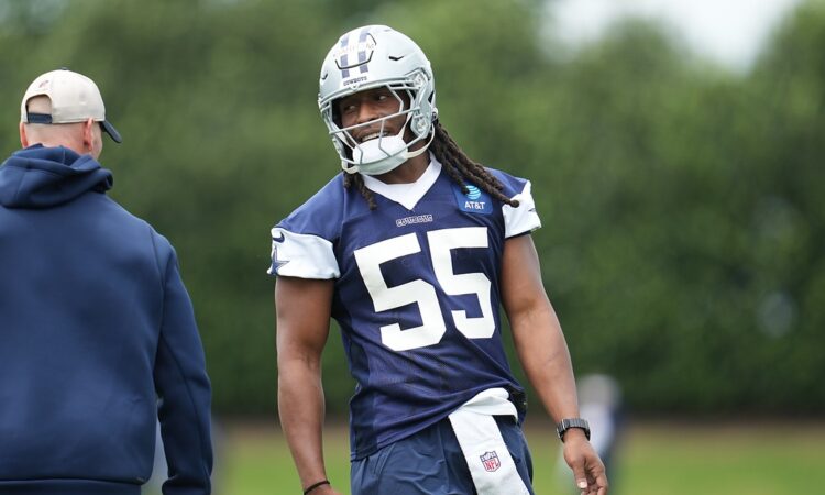 Dallas Cowboys linebacker Jaishawn Barham smiles toward a coach while standing on the practice field in helmet and jersey.