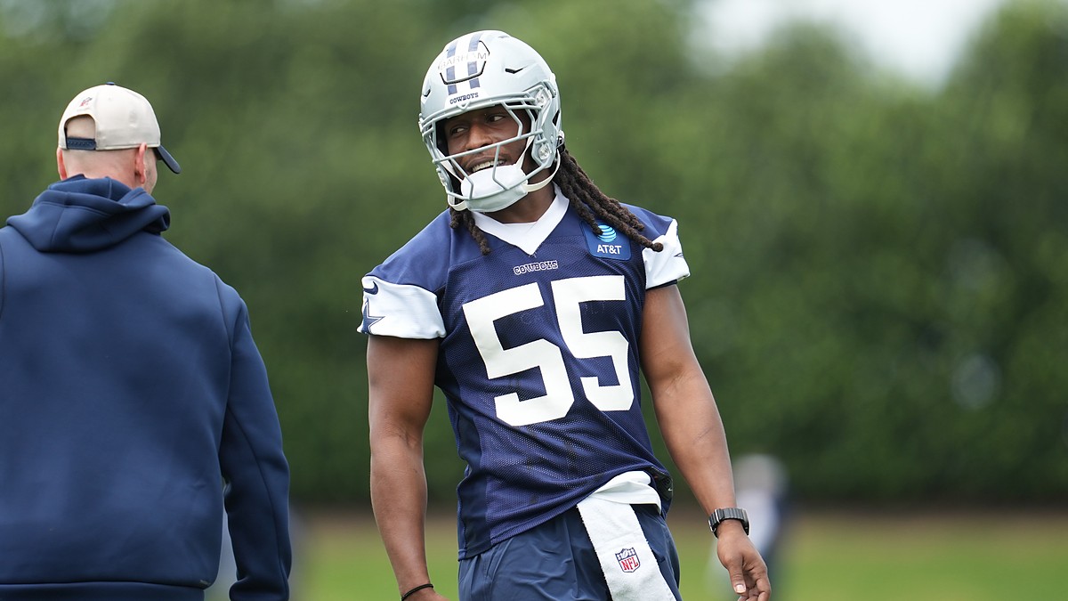 Dallas Cowboys linebacker Jaishawn Barham smiles toward a coach while standing on the practice field in helmet and jersey.