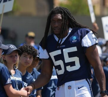 Dallas Cowboys linebacker Jaishawn Barham greets young fans lined up along the sideline at training camp.