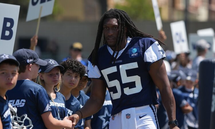 Dallas Cowboys linebacker Jaishawn Barham greets young fans lined up along the sideline at training camp.