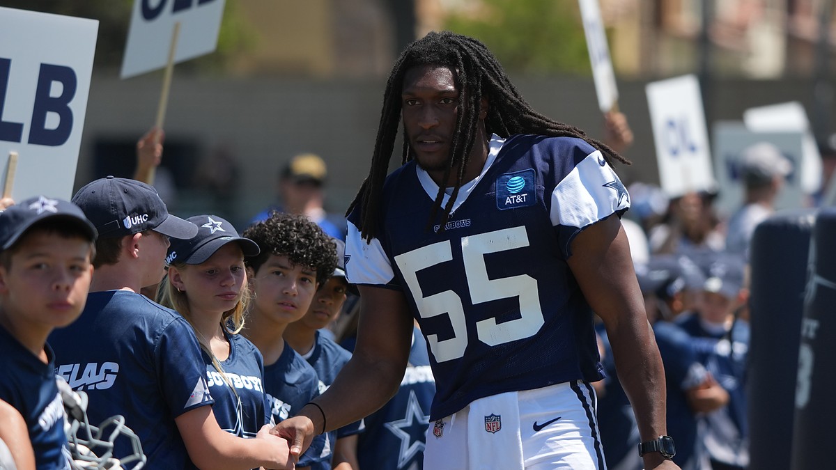Dallas Cowboys linebacker Jaishawn Barham greets young fans lined up along the sideline at training camp.
