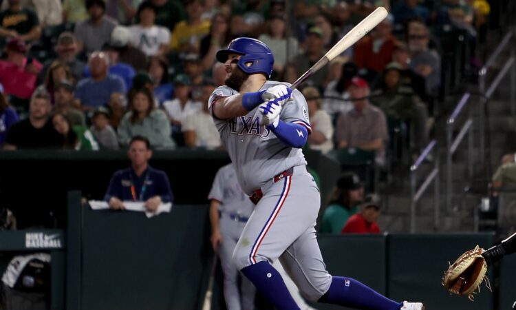 Texas Rangers first baseman Jake Burger follows through on his swing after connecting against the Athletics.