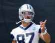 Dallas Cowboys tight end Jake Ferguson gestures with one hand during training camp in his No. 87 practice jersey.