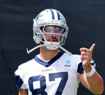 Dallas Cowboys tight end Jake Ferguson gestures with one hand during training camp in his No. 87 practice jersey.
