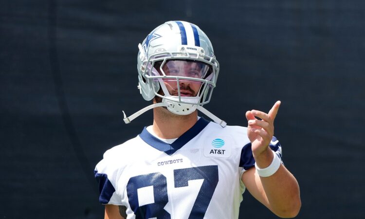 Dallas Cowboys tight end Jake Ferguson gestures with one hand during training camp in his No. 87 practice jersey.