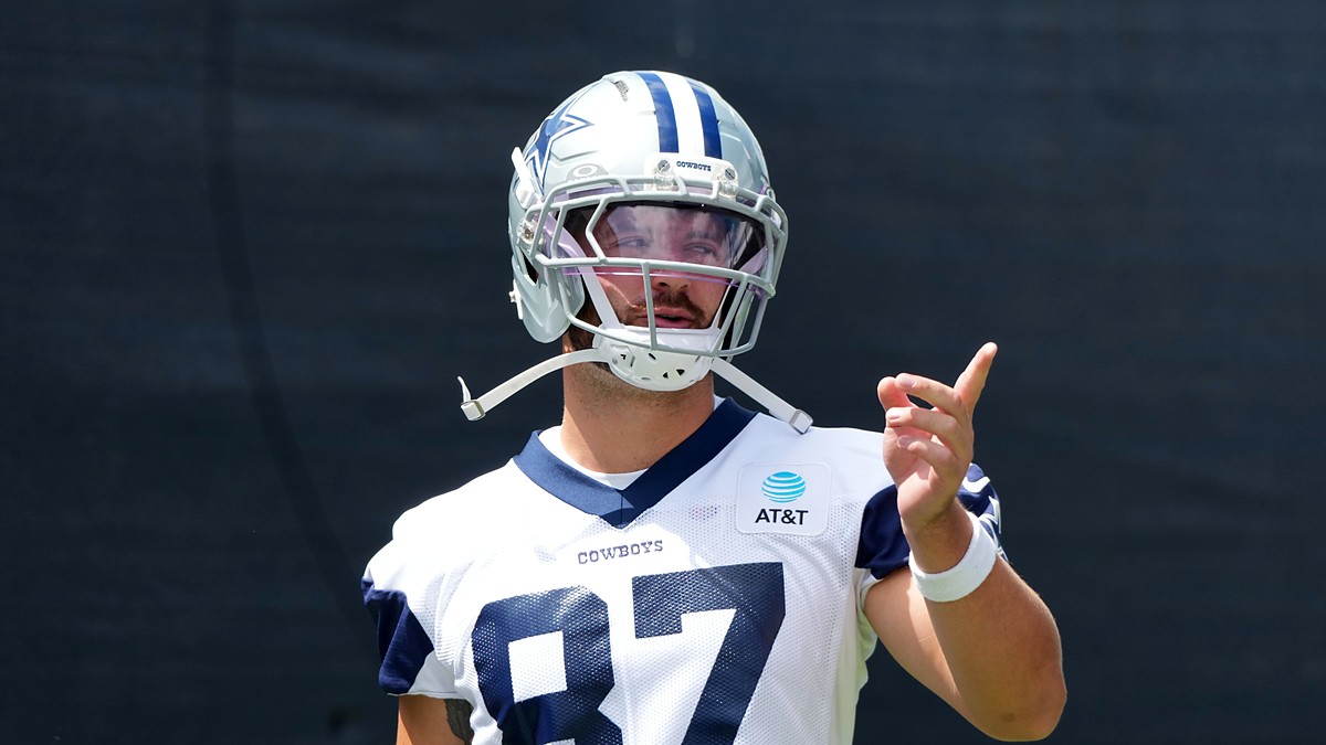 Dallas Cowboys tight end Jake Ferguson gestures with one hand during training camp in his No. 87 practice jersey.