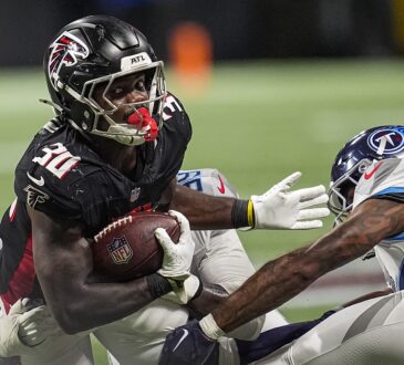Atlanta Falcons running back Jashaun Corbin secures the football as two Tennessee Titans defenders close in.