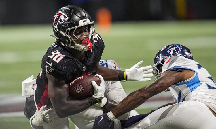 Atlanta Falcons running back Jashaun Corbin secures the football as two Tennessee Titans defenders close in.