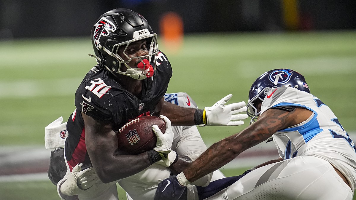 Atlanta Falcons running back Jashaun Corbin secures the football as two Tennessee Titans defenders close in.