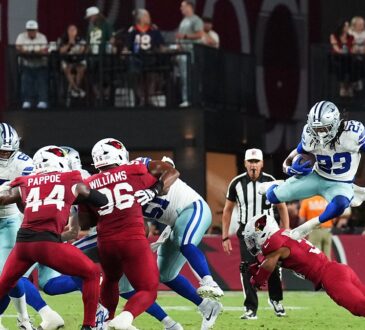 Dallas Cowboys running back Jaydon Blue leaps over a diving Cardinals defender on a first-half carry.