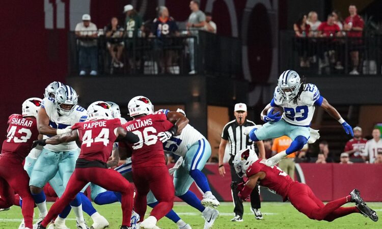 Dallas Cowboys running back Jaydon Blue leaps over a diving Cardinals defender on a first-half carry.