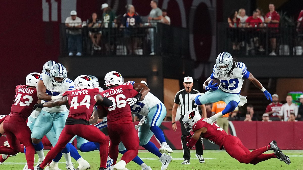 Dallas Cowboys running back Jaydon Blue leaps over a diving Cardinals defender on a first-half carry.