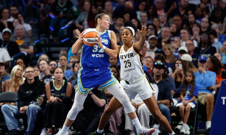 Dallas Wings forward Jessica Shepard secures the ball as Indiana Fever forward Monique Billings defends with both hands up.