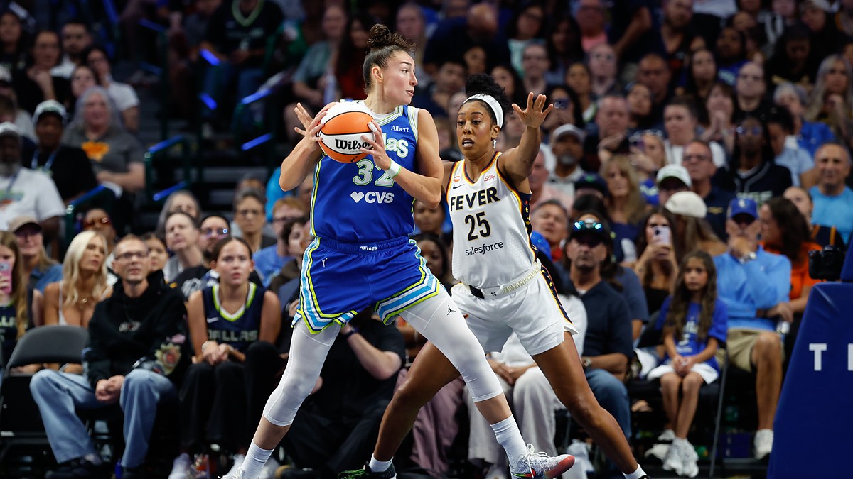 Dallas Wings forward Jessica Shepard secures the ball as Indiana Fever forward Monique Billings defends with both hands up.