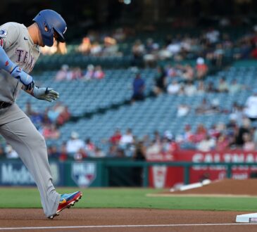Texas Rangers designated hitter Joc Pederson rounds third base with his head down after hitting a home run.