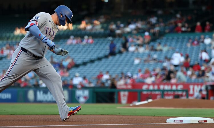 Texas Rangers designated hitter Joc Pederson rounds third base with his head down after hitting a home run.