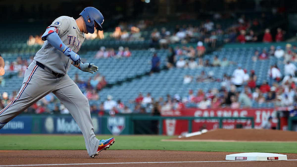Texas Rangers designated hitter Joc Pederson rounds third base with his head down after hitting a home run.