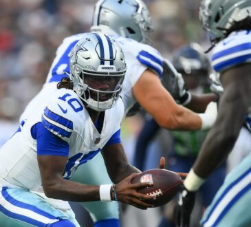 Dallas Cowboys quarterback Joe Milton III extends the ball on a handoff to a teammate in the backfield.