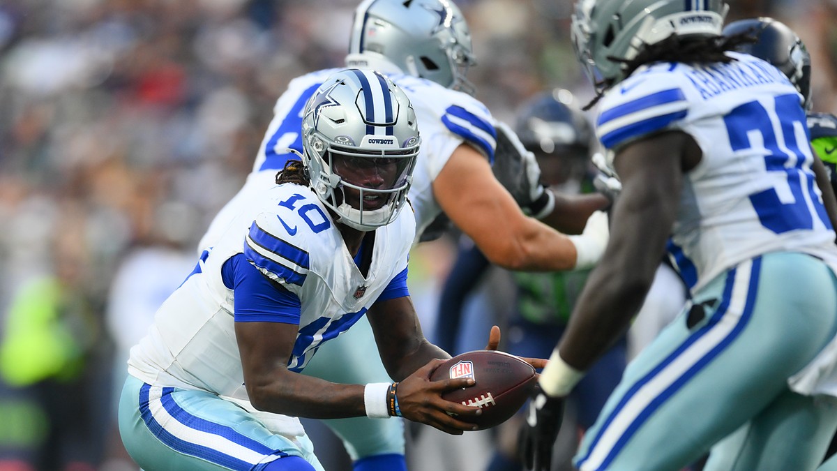 Dallas Cowboys quarterback Joe Milton III extends the ball on a handoff to a teammate in the backfield.
