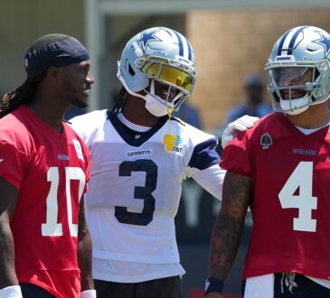 Dallas Cowboys wide receiver George Pickens smiles with an arm around quarterback Dak Prescott as Joe Milton III looks on.