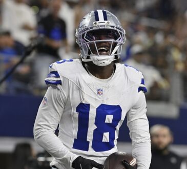 Dallas Cowboys wide receiver Jordan Hudson grins while holding the ball after scoring a touchdown.