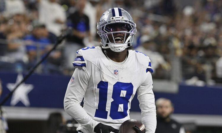 Dallas Cowboys wide receiver Jordan Hudson grins while holding the ball after scoring a touchdown.