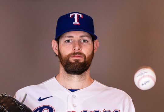 Texas Rangers pitcher Jordan Montgomery holds his glove and tosses a baseball during a media day portrait.
