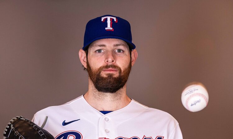 Texas Rangers pitcher Jordan Montgomery holds his glove and tosses a baseball during a media day portrait.