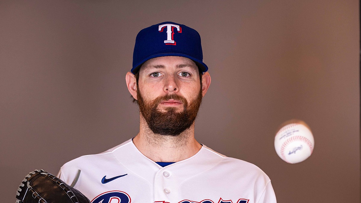 Texas Rangers pitcher Jordan Montgomery holds his glove and tosses a baseball during a media day portrait.