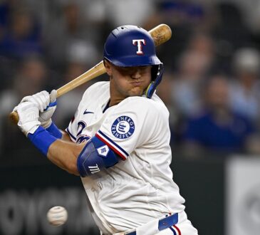 Texas Rangers third baseman Josh Jung turns away and winces as a pitch strikes him at the plate.