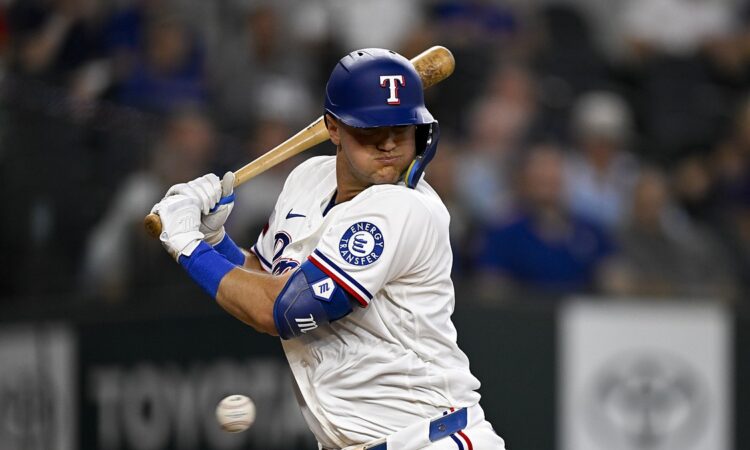 Texas Rangers third baseman Josh Jung turns away and winces as a pitch strikes him at the plate.