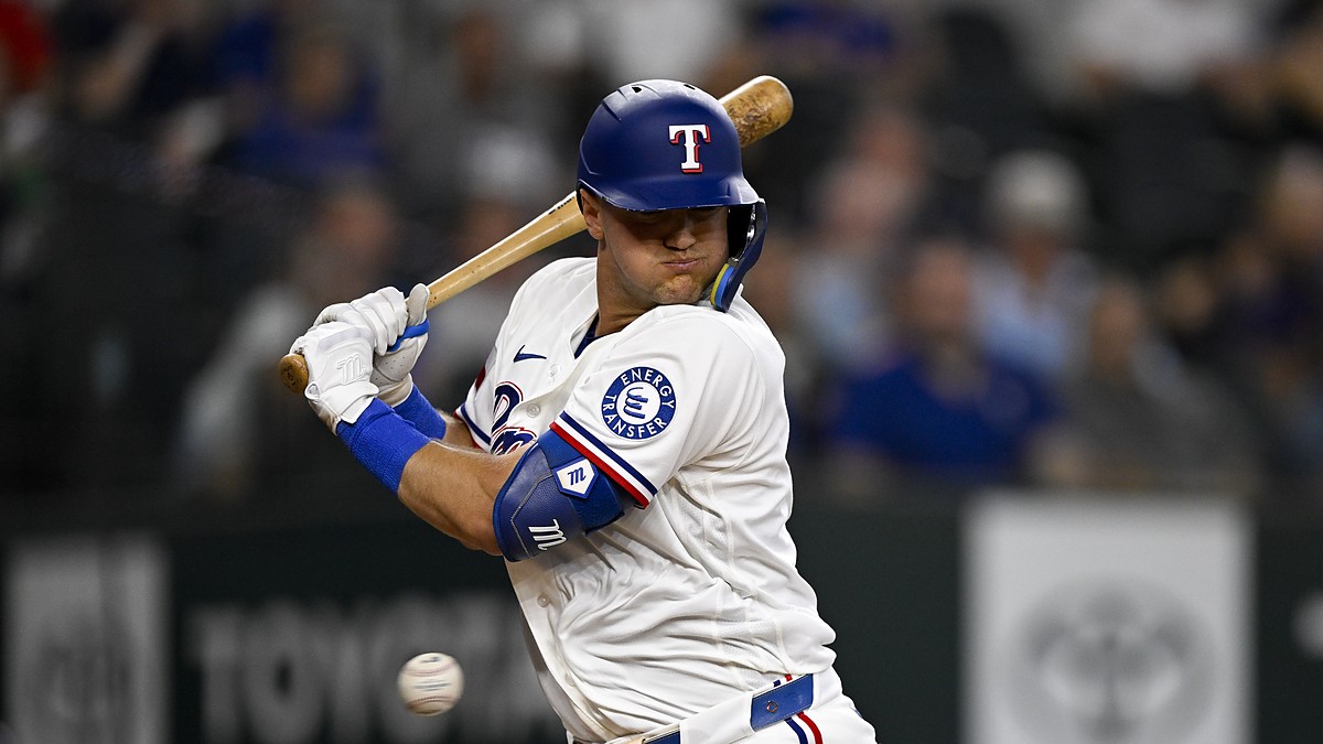 Texas Rangers third baseman Josh Jung turns away and winces as a pitch strikes him at the plate.
