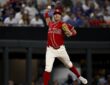 Texas Rangers third baseman Josh Jung cocks his arm to throw across the diamond in a red Tejas City Connect uniform.