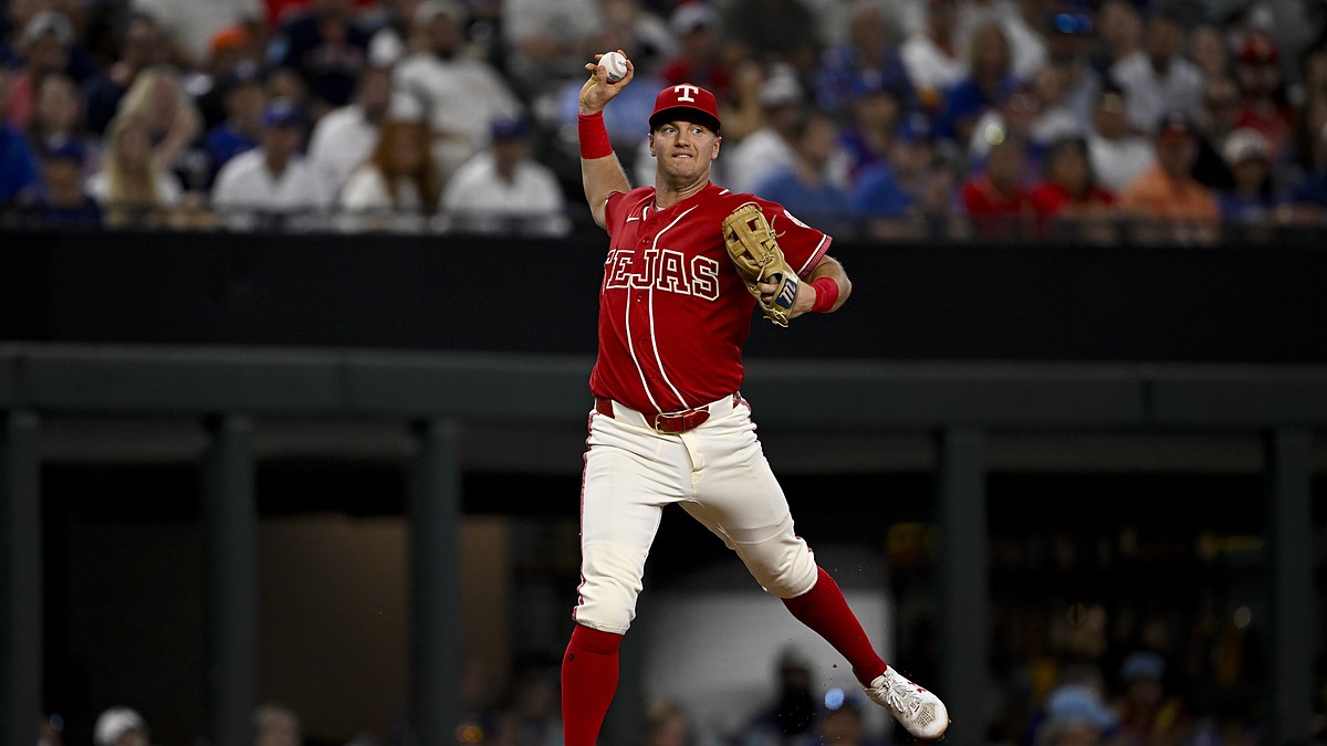 Texas Rangers third baseman Josh Jung cocks his arm to throw across the diamond in a red Tejas City Connect uniform.