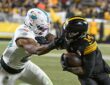 Pittsburgh Steelers running back Kenneth Gainwell tucks the ball and shrugs off a grab by Dolphins linebacker Jordyn Brooks.