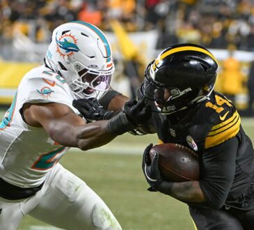 Pittsburgh Steelers running back Kenneth Gainwell tucks the ball and shrugs off a grab by Dolphins linebacker Jordyn Brooks.