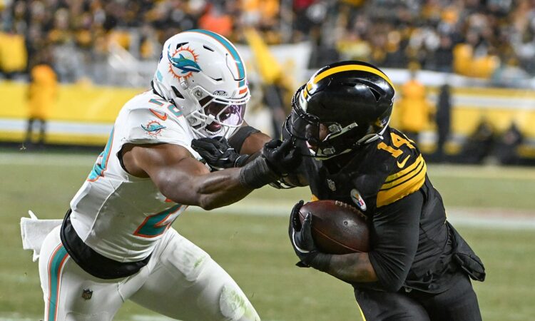 Pittsburgh Steelers running back Kenneth Gainwell tucks the ball and shrugs off a grab by Dolphins linebacker Jordyn Brooks.