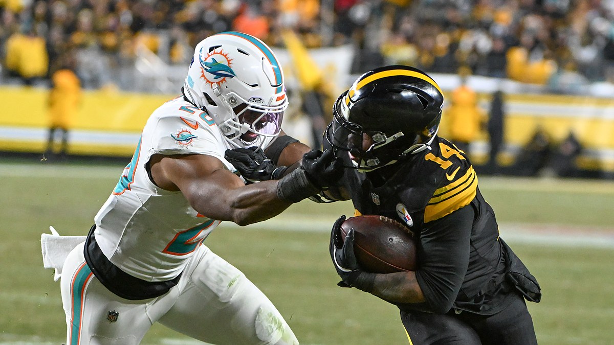 Pittsburgh Steelers running back Kenneth Gainwell tucks the ball and shrugs off a grab by Dolphins linebacker Jordyn Brooks.